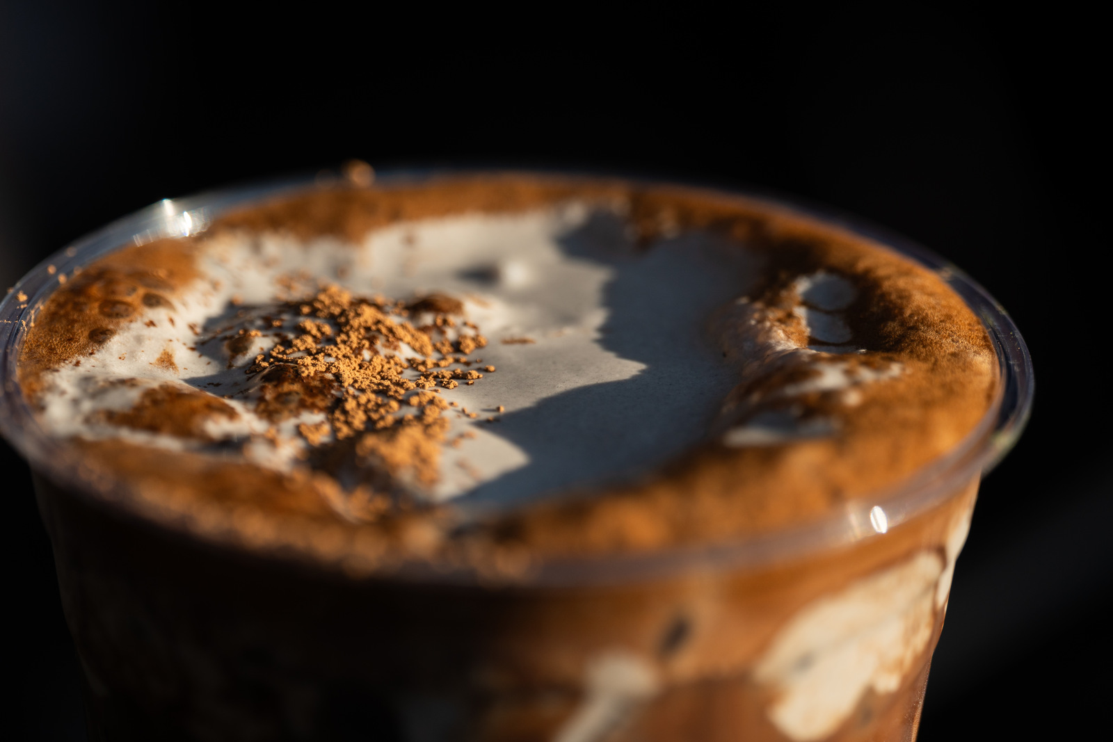 A black-sesame hojicha latte topped with a grey cloud of foam and dusted hojicha