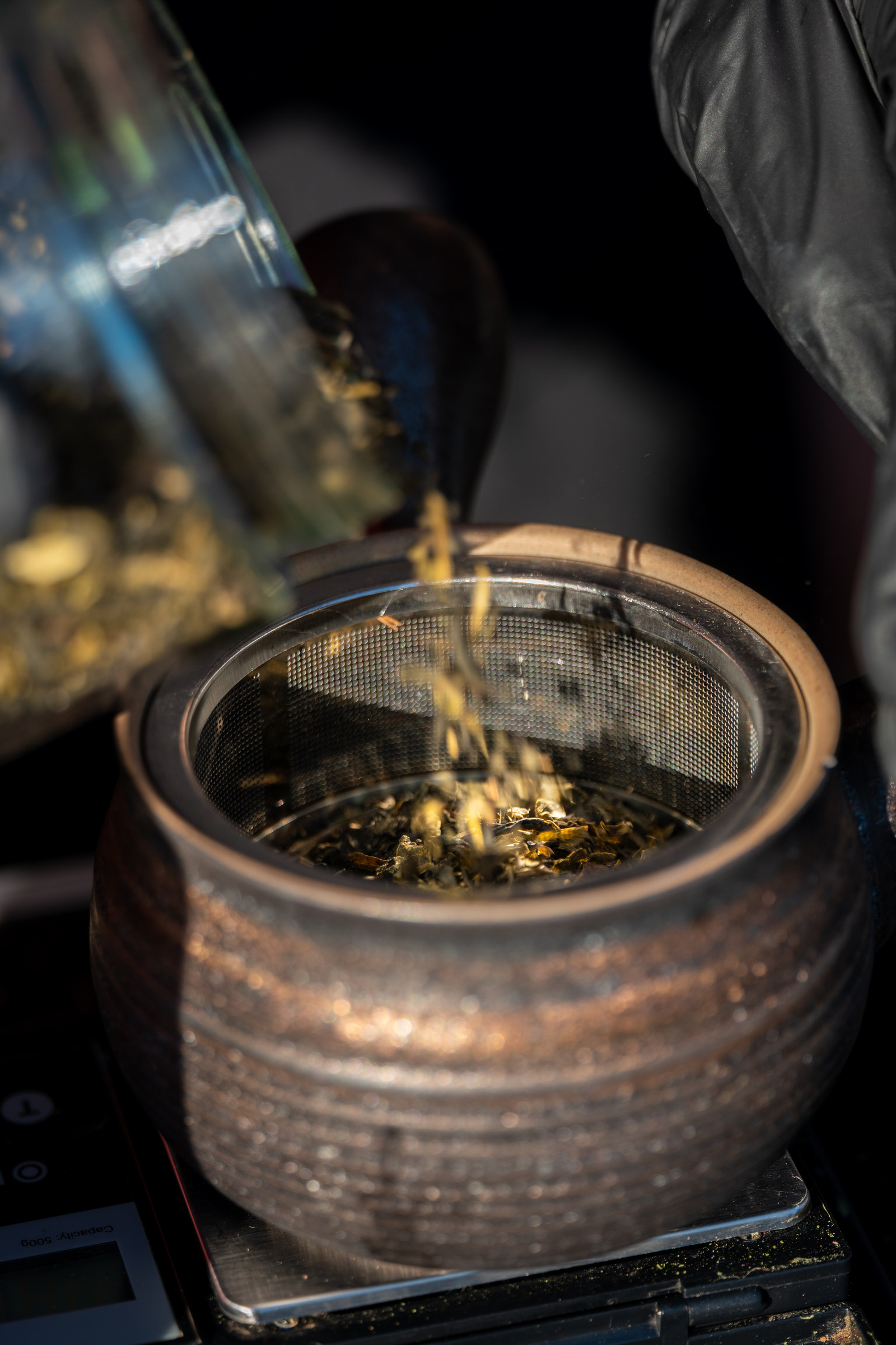 Jasmine green tea leaves being poured into a ceramic kyusu