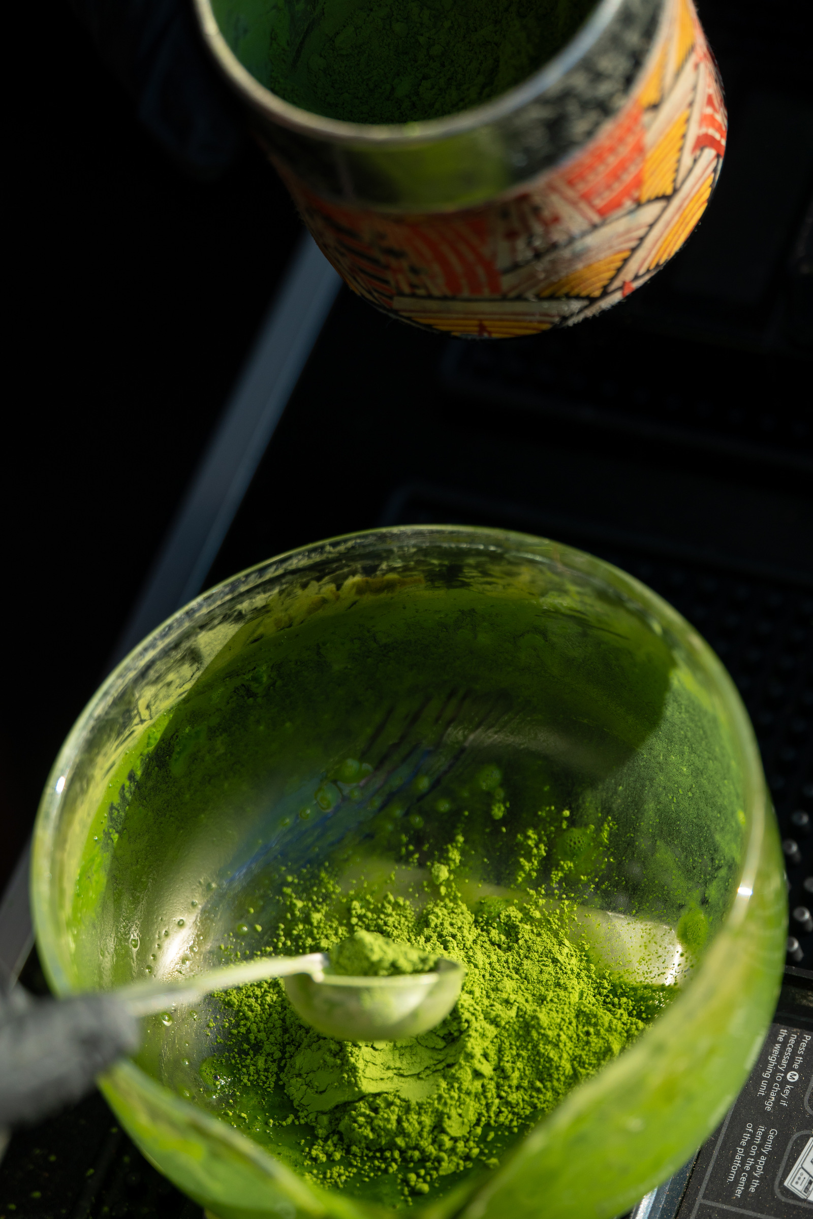 Vibrant green M099 ceremonial matcha powder in a glass bowl, seen from above