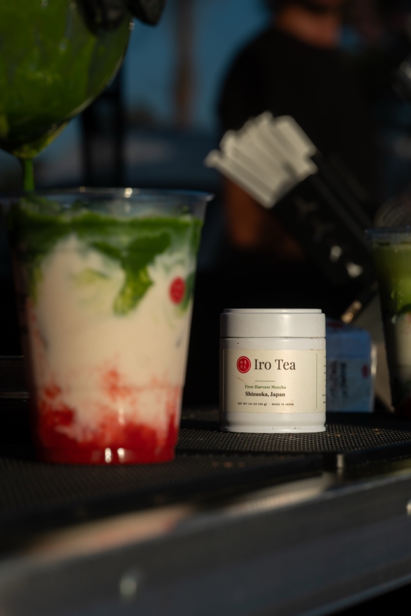 The M099 tin on the bar at an Iro Tea market stand, beside a layered strawberry matcha