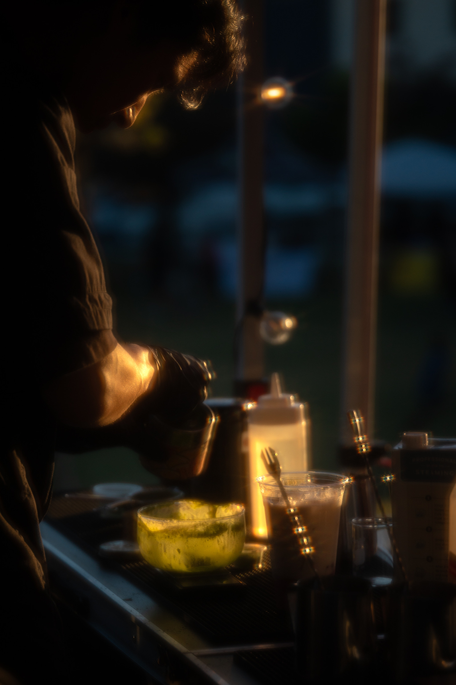 An Iro Tea operator preparing drinks at the booth after dark