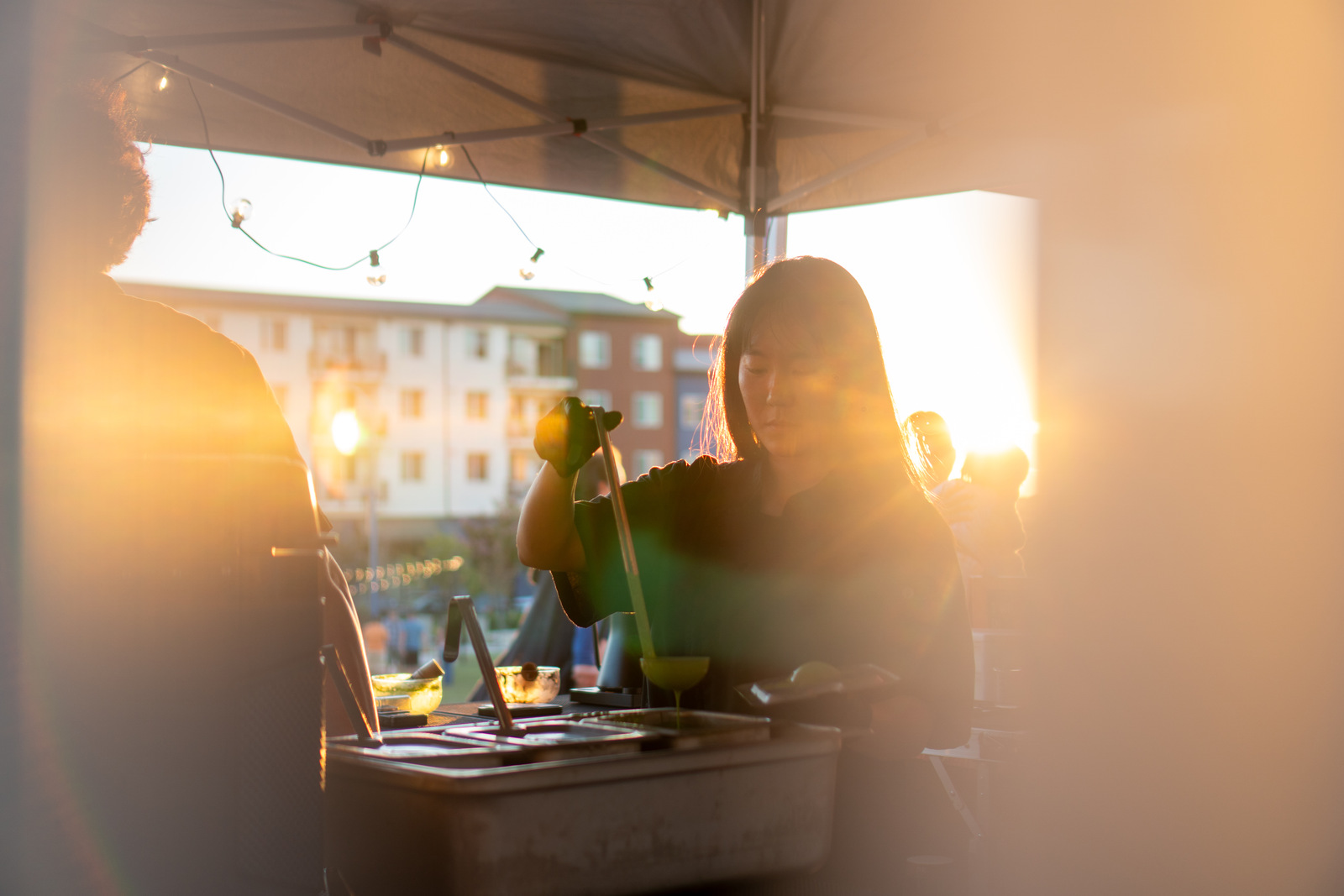 An Iro Tea operator at the market booth in bright sun flare